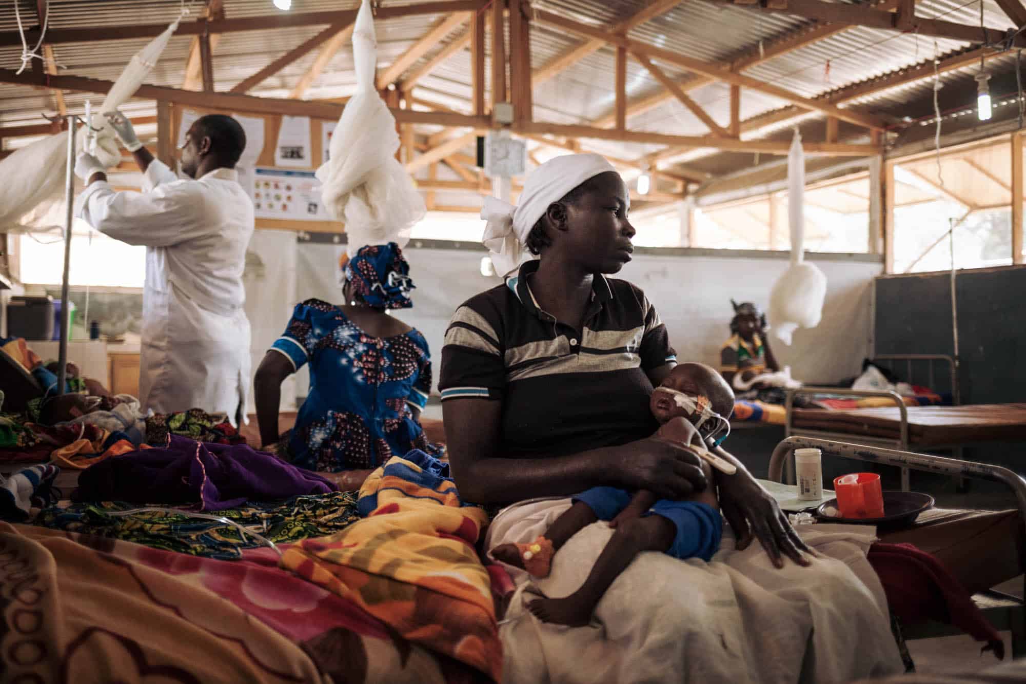 Marie GODAM et sa fille de 10 mois, Dawaï KONAÏ. Dawaï a été admise la veille en soins intensifs pédiatriques à l'hôpital de Mokolo en état convulsif avec 40,5°C de fièvre. Les médecins suspectent un cas de méningite. Elle souffre également de malnutrition, à 10 mois elle pèse 5,6 kg et mesure 65 cm. Mokolo, Région Extrême-Nord, Cameroun. PHOTO: ALEXIS HUGUET/ALIMA
