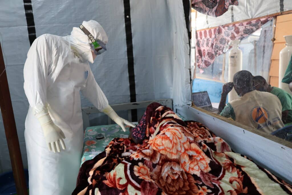 Un médecin en consultation auprès d'un patient atteint de la maladie à virus Ebola dans le CTE d'ALIMA à Rwampara.
