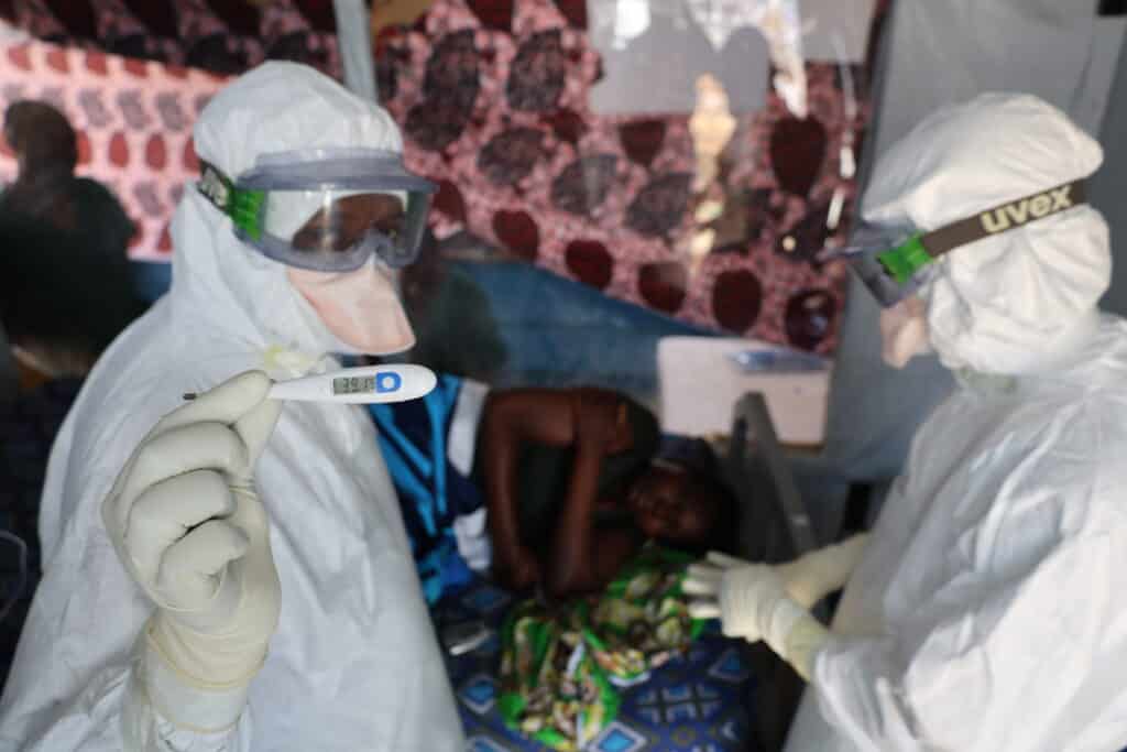 Deux médecins en prise en charge d'une patiente atteinte d'Ebola relevant sa température au CTE d'ALIMA à Rwampara.