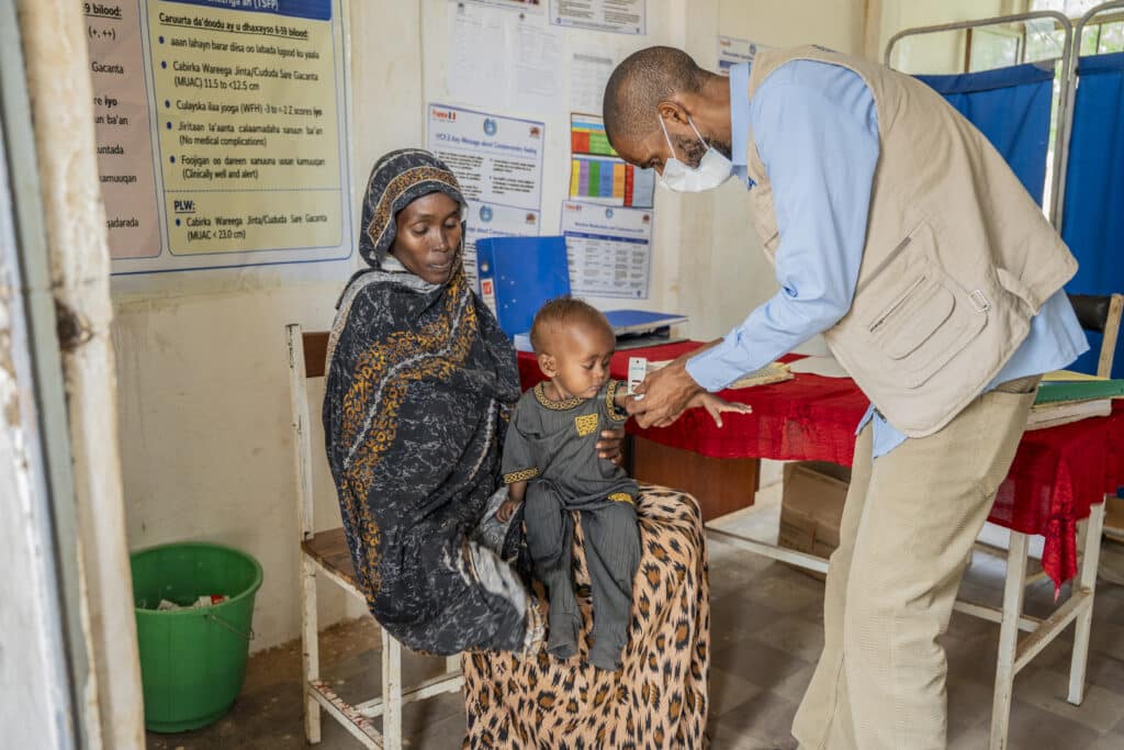 Infirmier mesurant le périmètre brachial d'un enfant malnourished avec un ruban PB (MUAC) et distribuant des sachets de Plumpy'Nut au centre de santé d'Elkare.